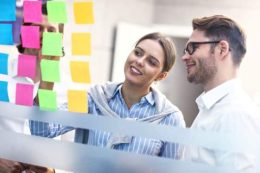 two happy business people looking at sticky notes in a workshop